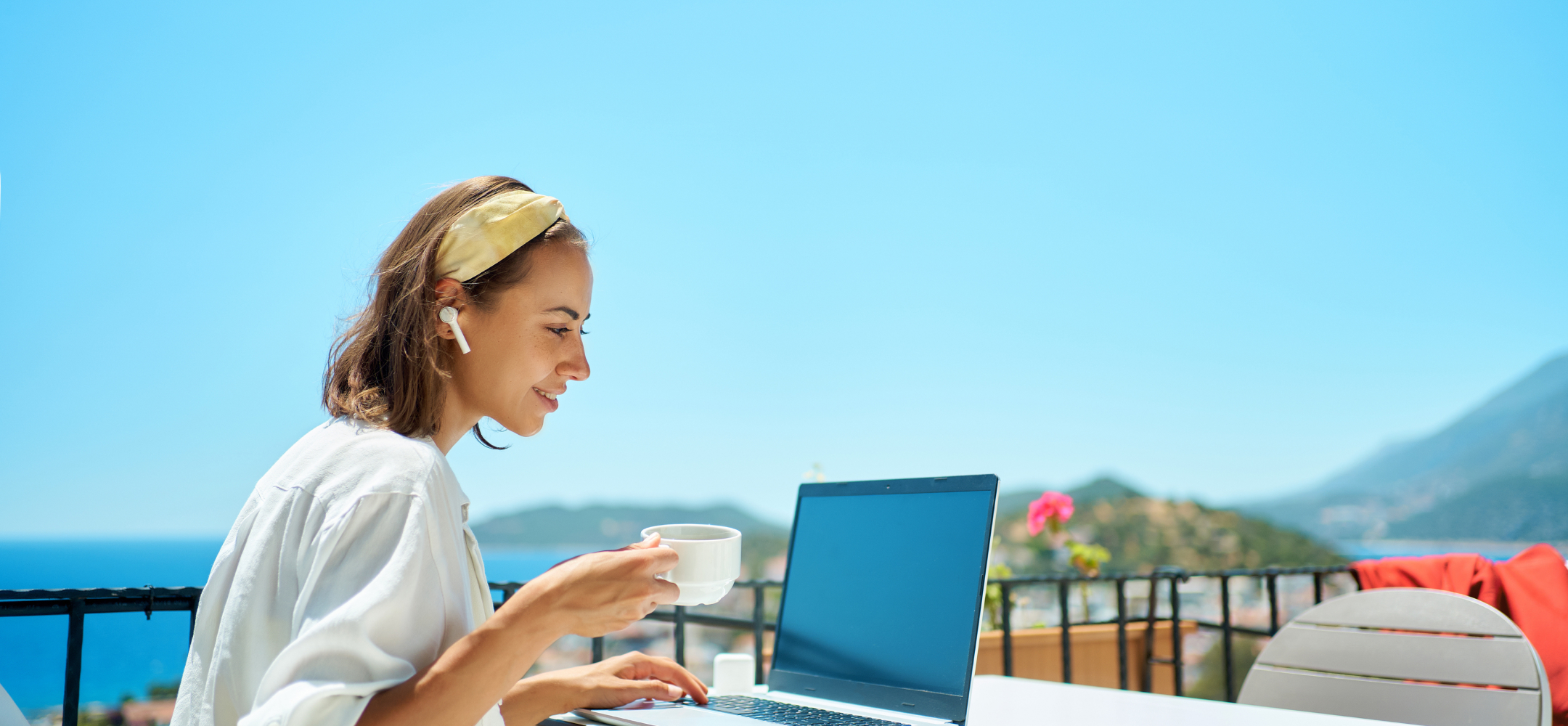 女性が海の見えるテラスでPCを広げている写真