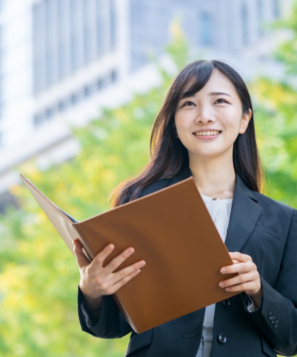 女性がファイルを持ちながら前を向いている写真